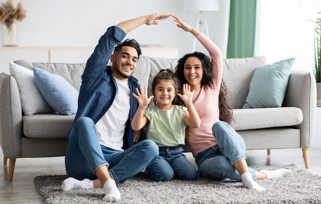 Happy family sitting on the carpet in their house